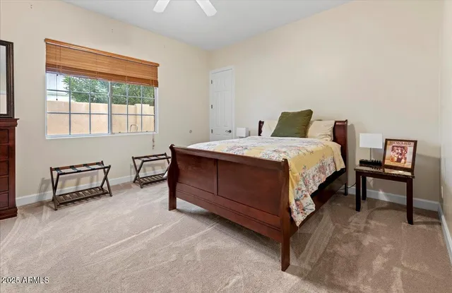 a bedroom with a bed table chair and a window
