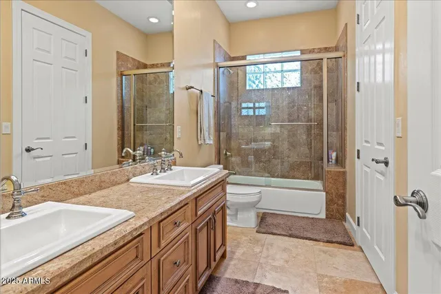 a bathroom with a granite countertop sink a toilet a mirror and shower