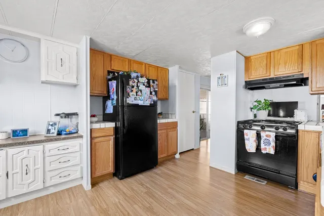a kitchen with granite countertop a refrigerator stove and wooden floor