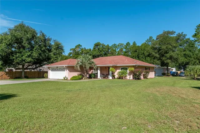 a view of a house with a big yard plants and large trees