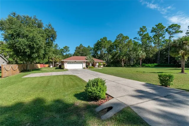 a view of a house with a yard and a large tree
