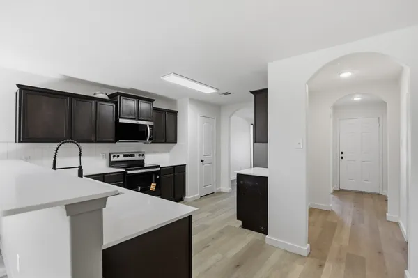 a kitchen with stainless steel appliances a sink a stove a microwave and wooden floors