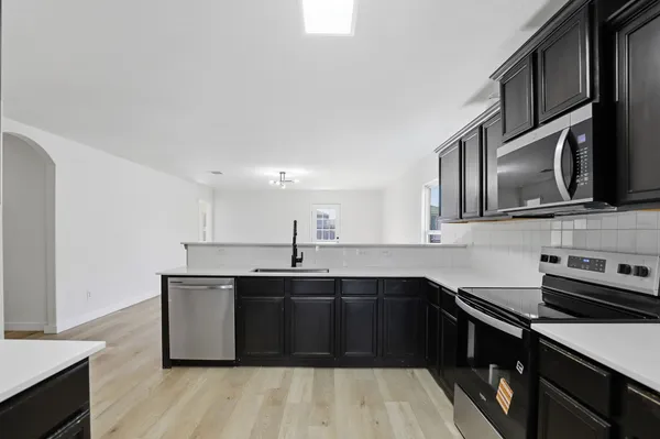 a view of kitchen and empty room with wooden floor
