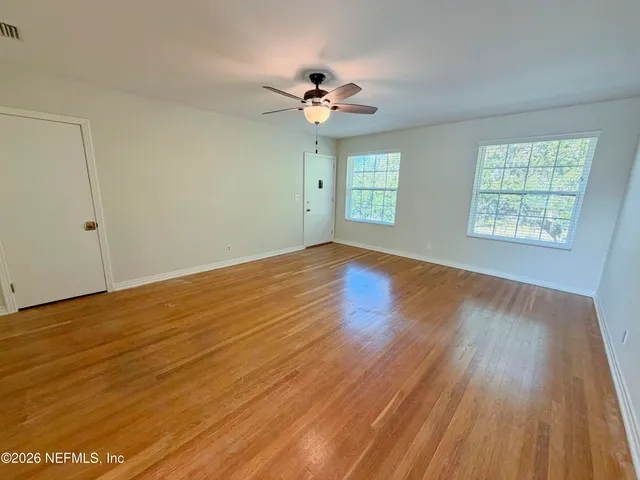 a view of an empty room with wooden floor and a window