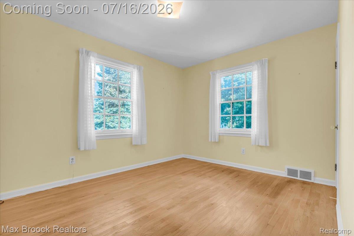 1292 Yorkshire Road Birmingham, MI 48009 - Photo 25 of 47 Room featuring wood-finish flooring, two large windows with white trim, a ceiling-mounted light fixture, and pale yellow walls with white baseboards