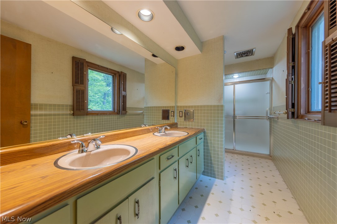 25001 Letchworth Road Beachwood, OH 44122 - Photo 27 of 50 Bathroom featuring a dual vanity with wood-finish countertop, two integrated sinks, and green cabinetry