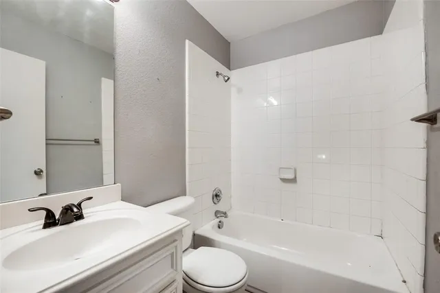 a bathroom with a bathtub shower sink vanity mirror and toilet