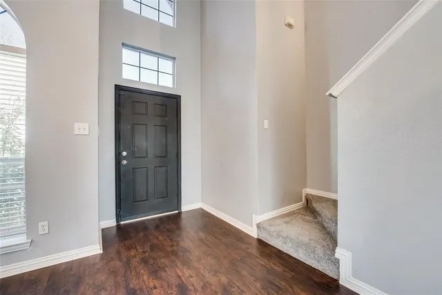 an empty room with wooden floor closet and windows