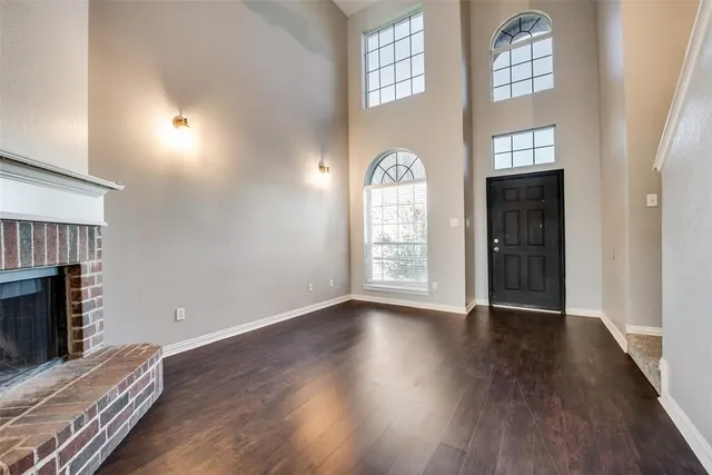 an empty room with windows fireplace and wooden floor
