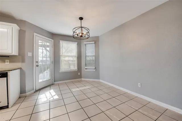 a view of an empty room with window and chandelier fan