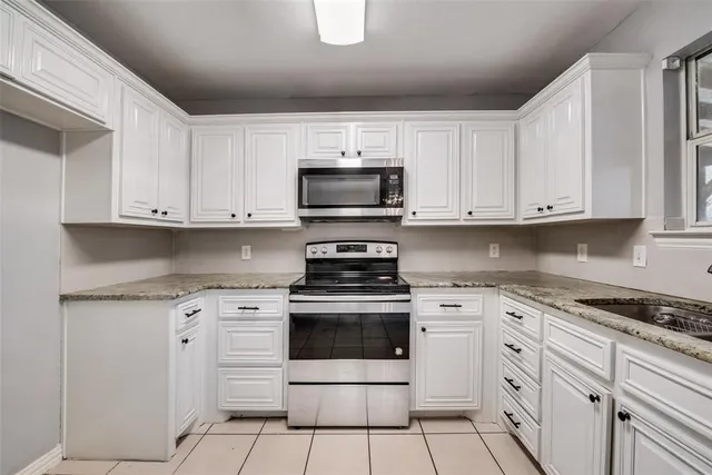 a kitchen with granite countertop white cabinets and appliances