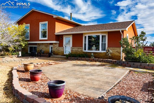 8115 Mustang Road Colorado Springs, CO 80908 - Photo 2 of 48 Back of property featuring brick siding, stucco siding, a shingled roof, and a patio