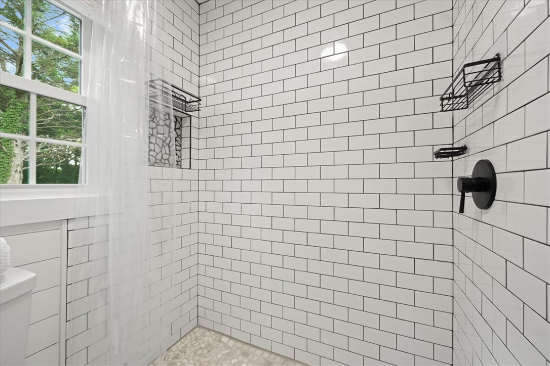 174 Holliday Road Six Mile, SC 29682 - Photo 32 of 49 A well-lit shower features white subway tile, a window, and black fixtures for a contemporary design