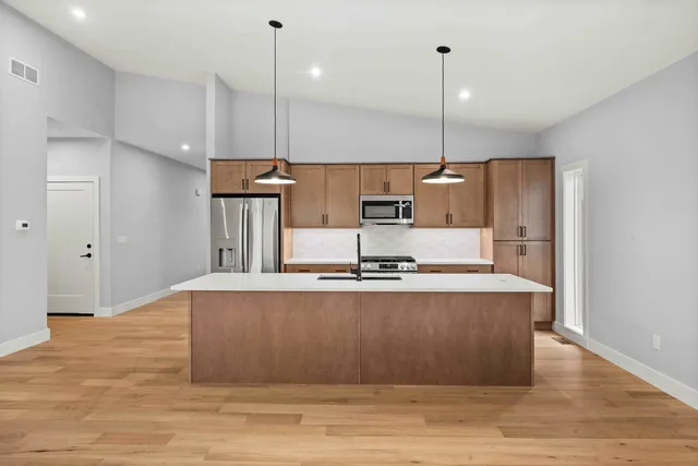 a kitchen with stainless steel appliances granite countertop a sink a refrigerator a stove a oven and wooden floor