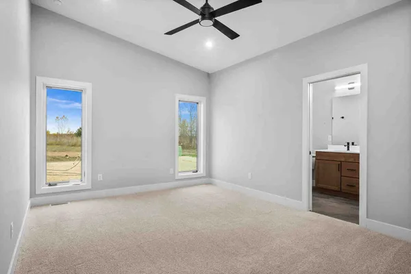 an empty room with windows and ceiling fan