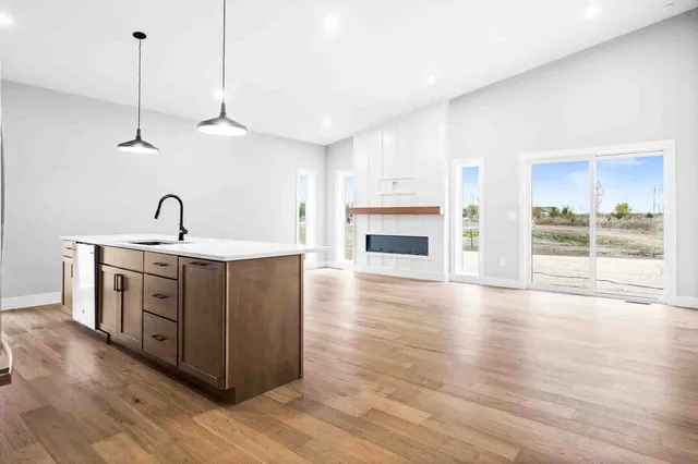 a kitchen with stainless steel appliances granite countertop a sink a stove and a wooden floor