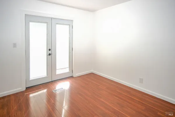 an empty room with wooden floor and windows