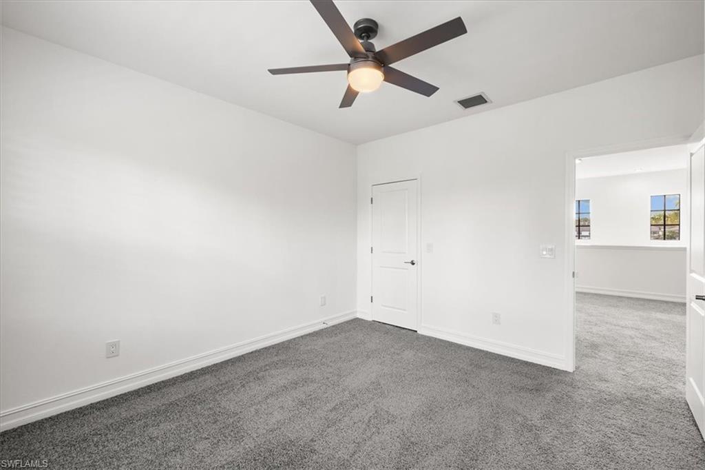 7622 Rockefeller Drive Naples, FL 34119 - Photo 19 of 40 an empty room with a ceiling fan and carpet
