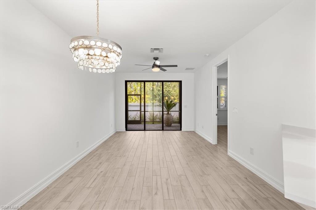 7622 Rockefeller Drive Naples, FL 34119 - Photo 9 of 40 an empty room with wooden floor chandelier and windows
