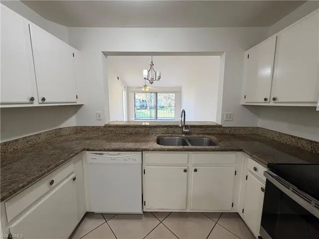 a kitchen with granite countertop white cabinets and a stove