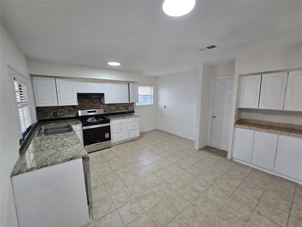 a kitchen with granite countertop a stove a sink and a refrigerator