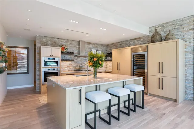 a kitchen with stainless steel appliances kitchen island granite countertop a table chairs and a refrigerator