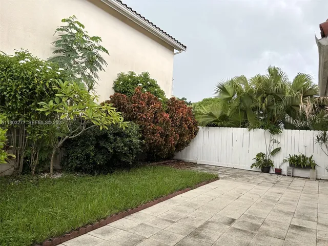 a view of backyard with potted plants and large tree