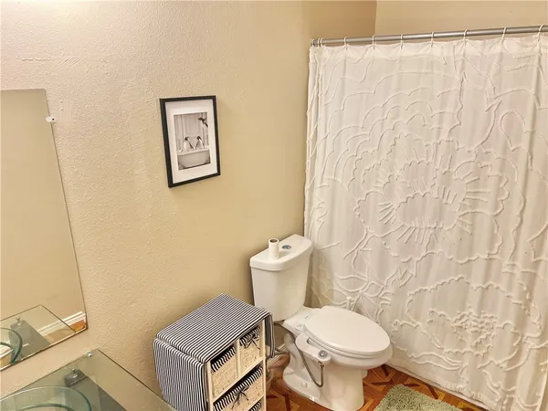 a white toilet sitting next to a white sink and a shower curtain
