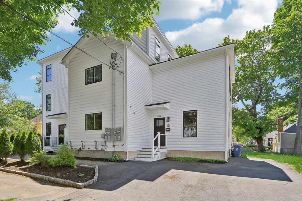 49 A Chestnut Street, Unit 1 Wakefield, MA 01880 - Photo 20 of 22 a view of a white house with a small yard and large tree