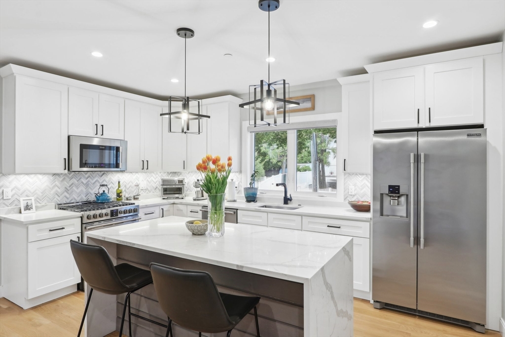 49 A Chestnut Street, Unit 1 Wakefield, MA 01880 - Photo 2 of 22 a kitchen with stainless steel appliances kitchen island granite countertop a refrigerator a sink a dining table and chairs