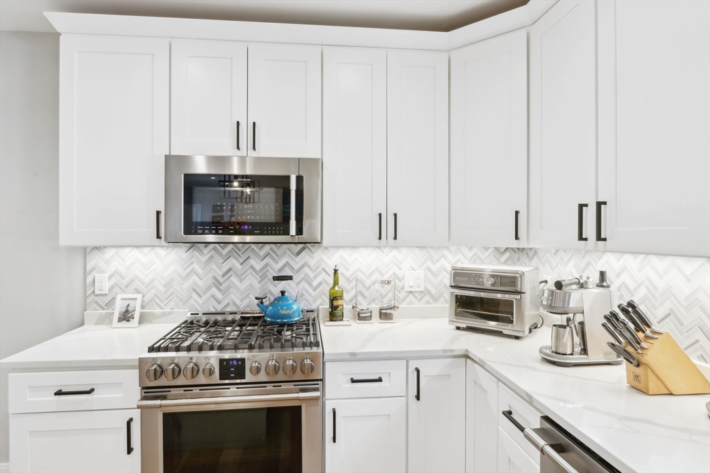 49 A Chestnut Street, Unit 1 Wakefield, MA 01880 - Photo 3 of 22 a kitchen with stainless steel appliances granite countertop white cabinets and a stove a oven with white countertops