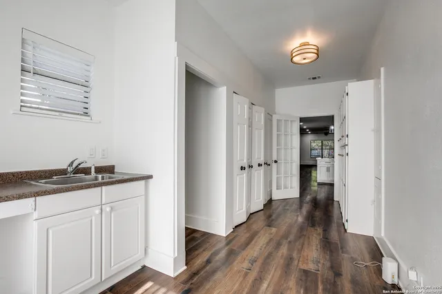 a kitchen with granite countertop a refrigerator a sink and wooden floor
