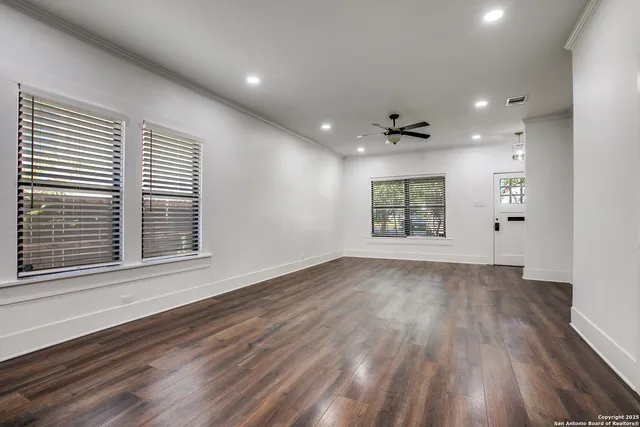 a view of an empty room with a window and wooden floor