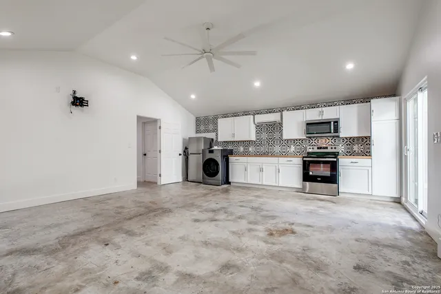 a kitchen with stainless steel appliances granite countertop a refrigerator oven a stove top oven and white cabinets