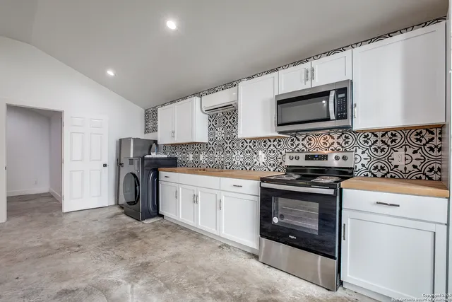 a kitchen with stainless steel appliances granite countertop grey cabinets a stove a sink and a microwave