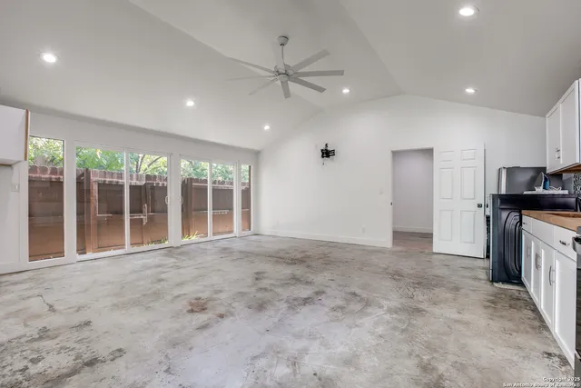 a view of an empty room with a kitchen view