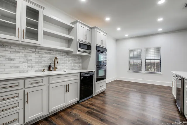 a kitchen with stainless steel appliances granite countertop a sink and wooden floors