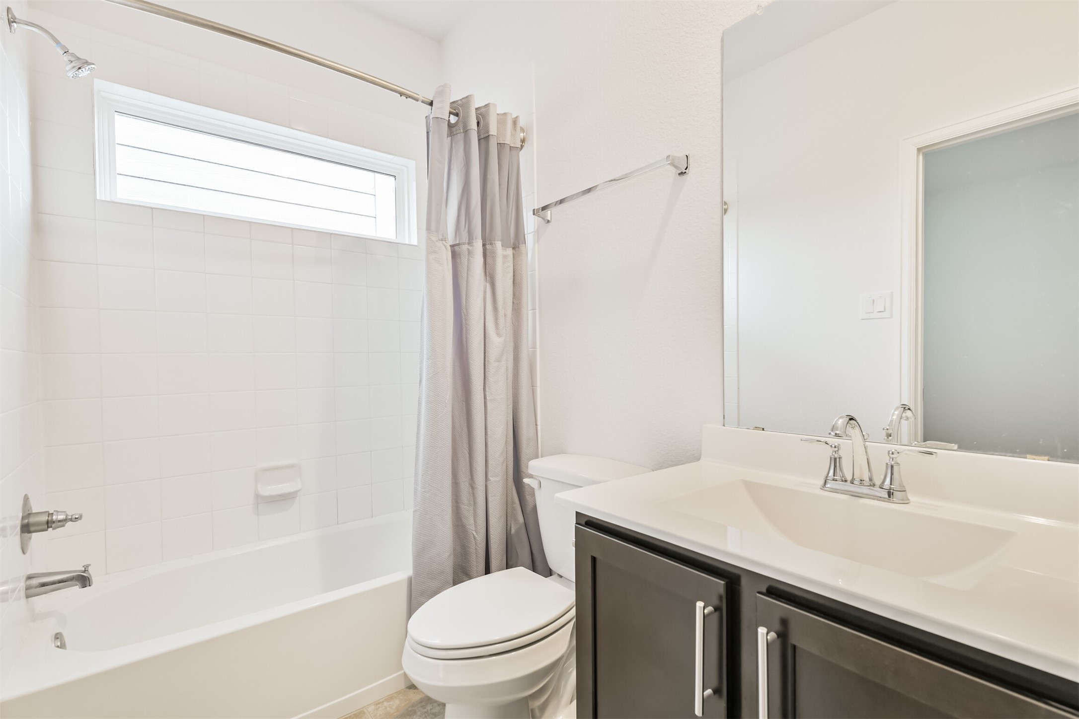 2129 Solstice Boulevard Spring, TX 77386 - Photo 33 of 49 Bright secondary bathroom with a clean tile tub/shower combo, modern fixtures, a large vanity with ample storage, and a transom window that brings in natural light while maintaining privacy.