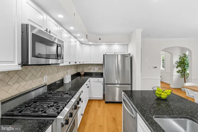 a kitchen with granite countertop a stove sink and refrigerator