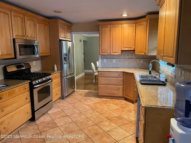 a kitchen with stainless steel appliances granite countertop a stove a sink and a refrigerator