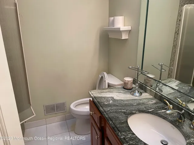 a bathroom with a granite countertop sink a toilet and a mirror