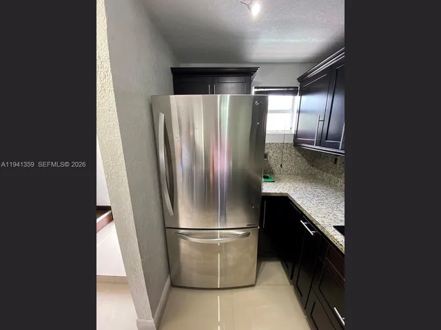 a metallic refrigerator freezer sitting inside of a kitchen