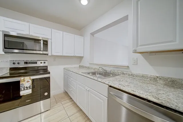 a kitchen with granite countertop white cabinets and a sink