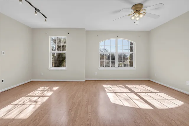 a view of an empty room with a window and wooden floor