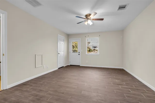 an empty room with windows and fan