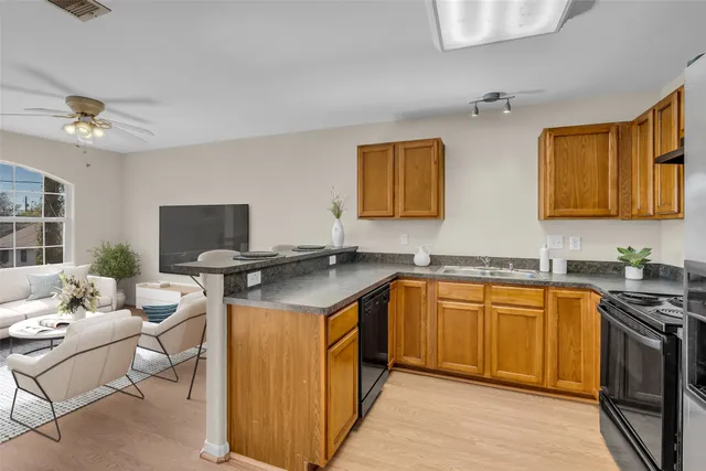 a open kitchen with stainless steel appliances granite countertop a sink dishwasher stove and refrigerator with wooden cabinets