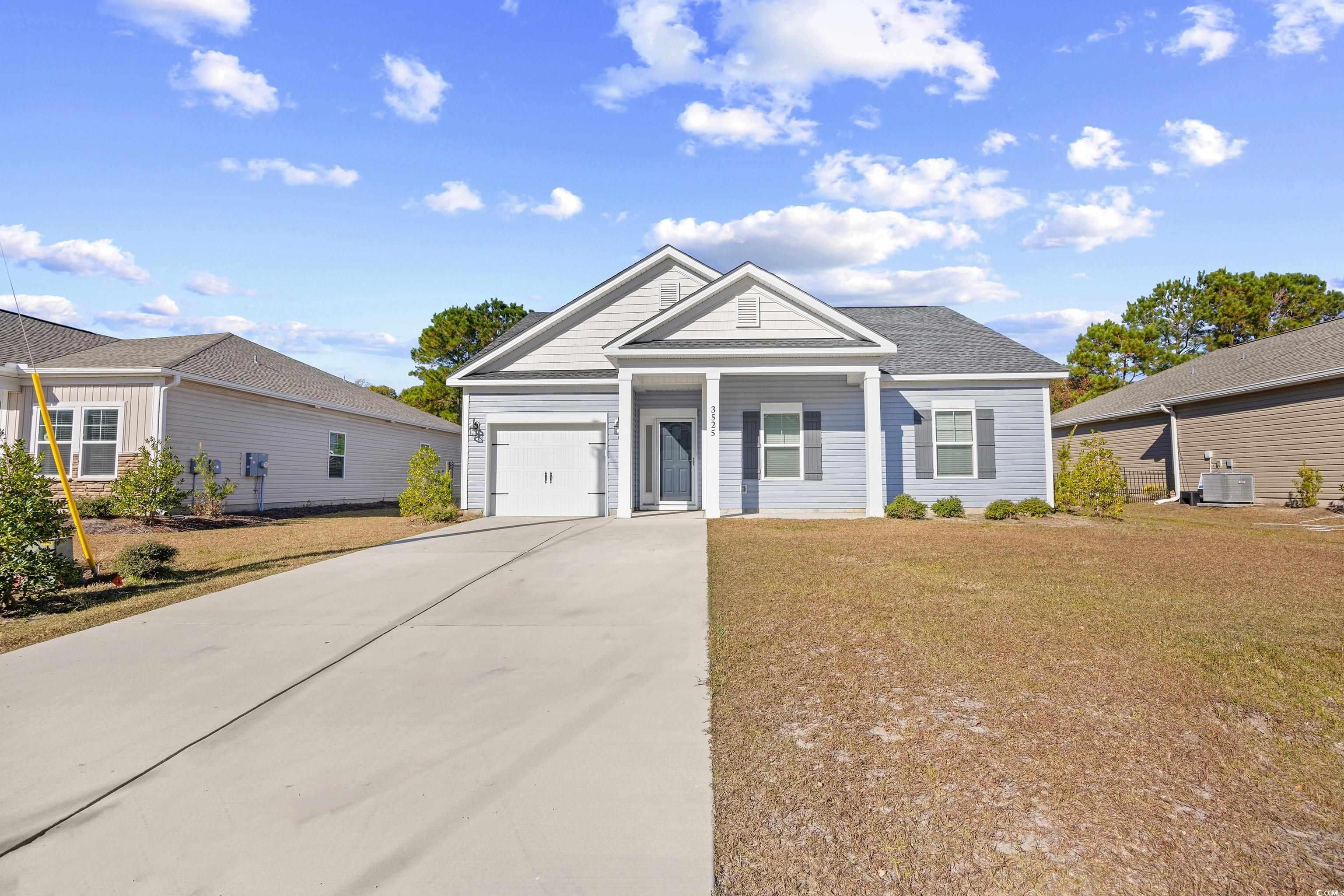 View of front of home with concrete driveway, a front yard, covered porch, and an attached garage