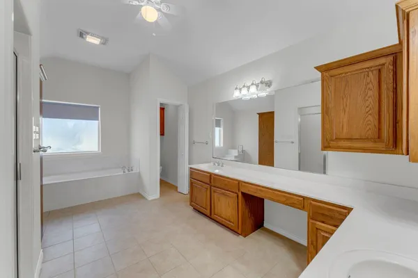 a spacious bathroom with a granite countertop sink a mirror and a bathtub