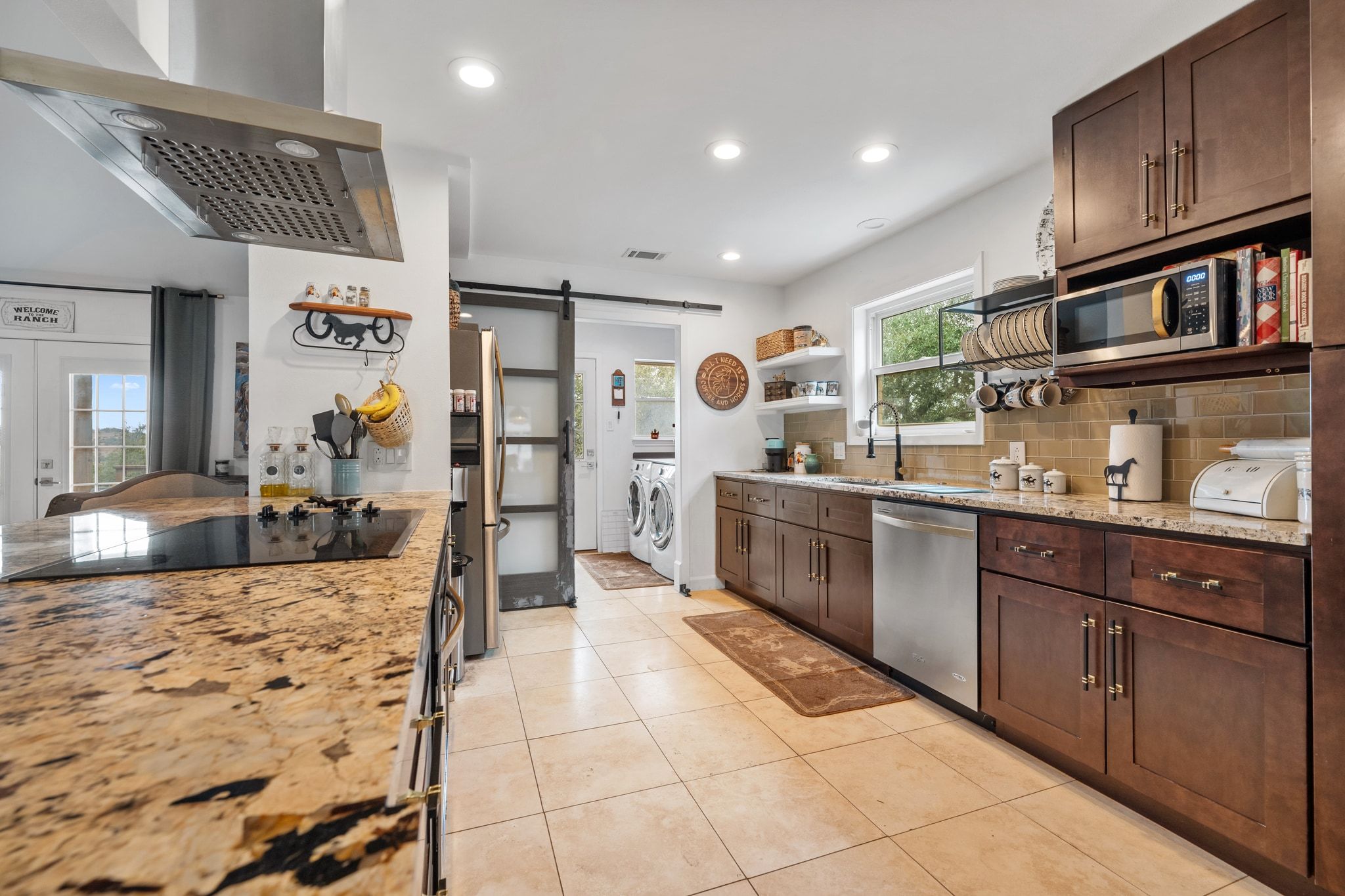 401 Ranchview Drive Johnson City, TX 78636 - Photo 16 of 40 Kitchen with exhaust hood, a barn door, light stone counters, dark wood finish cabinets, and stainless steel appliances