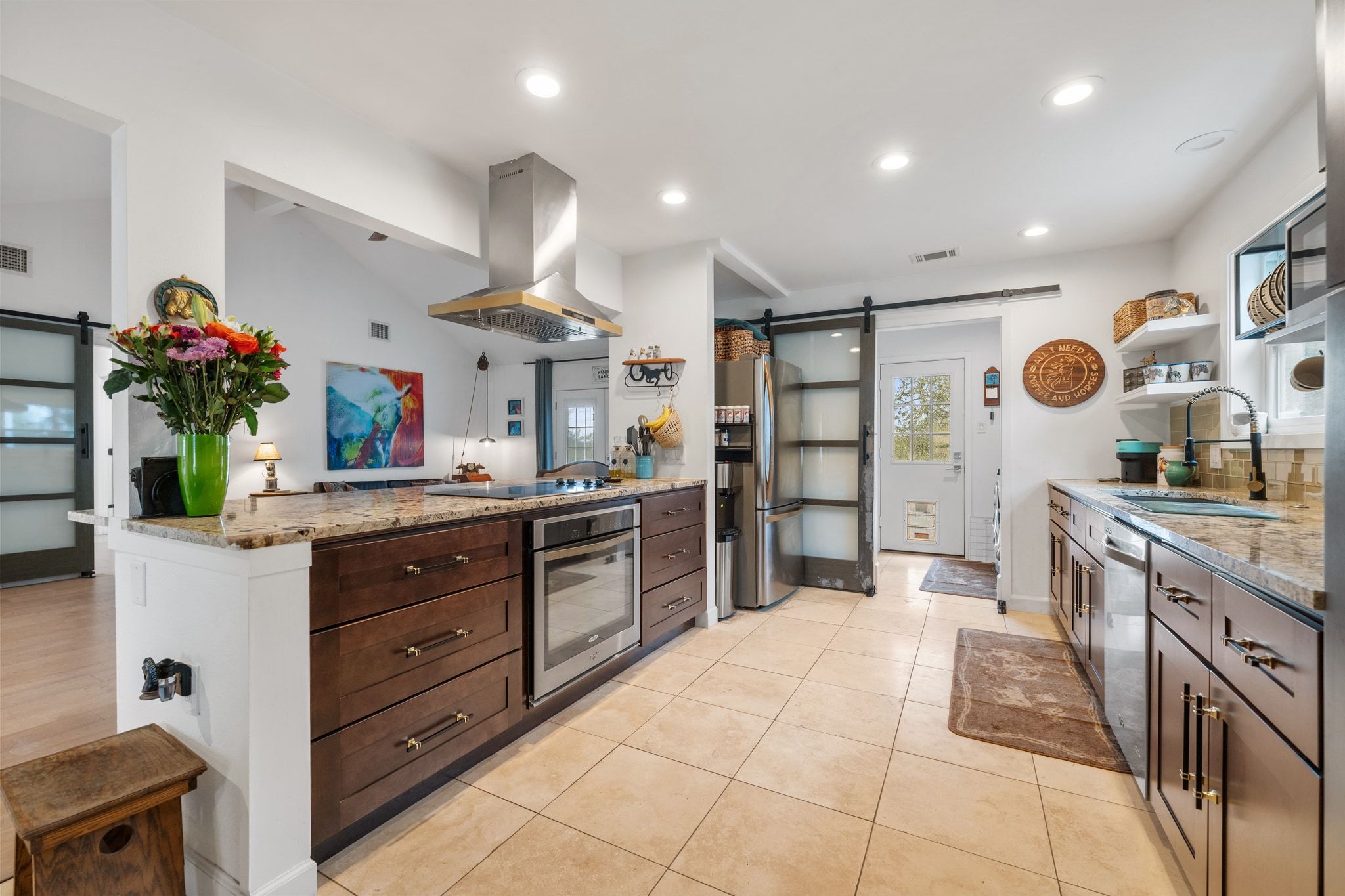 401 Ranchview Drive Johnson City, TX 78636 - Photo 17 of 40 Kitchen with a barn door, light stone countertops, dark wood finish cabinetry, island exhaust hood, and stainless steel appliances